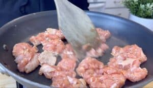 Cooking ground meat in skillet with wooden spatula on stovetop, perfect for savory meal preparation.